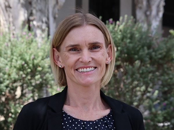 Woman with short blonde hair smiles while standing outside