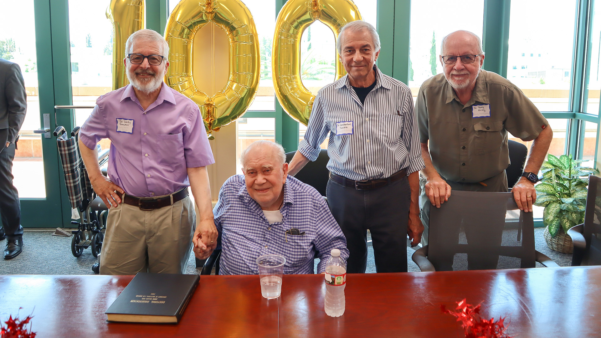 Sandy Bernstein, Jim Neel, Constantine Tsoukas, and Terry Frey pose at table.