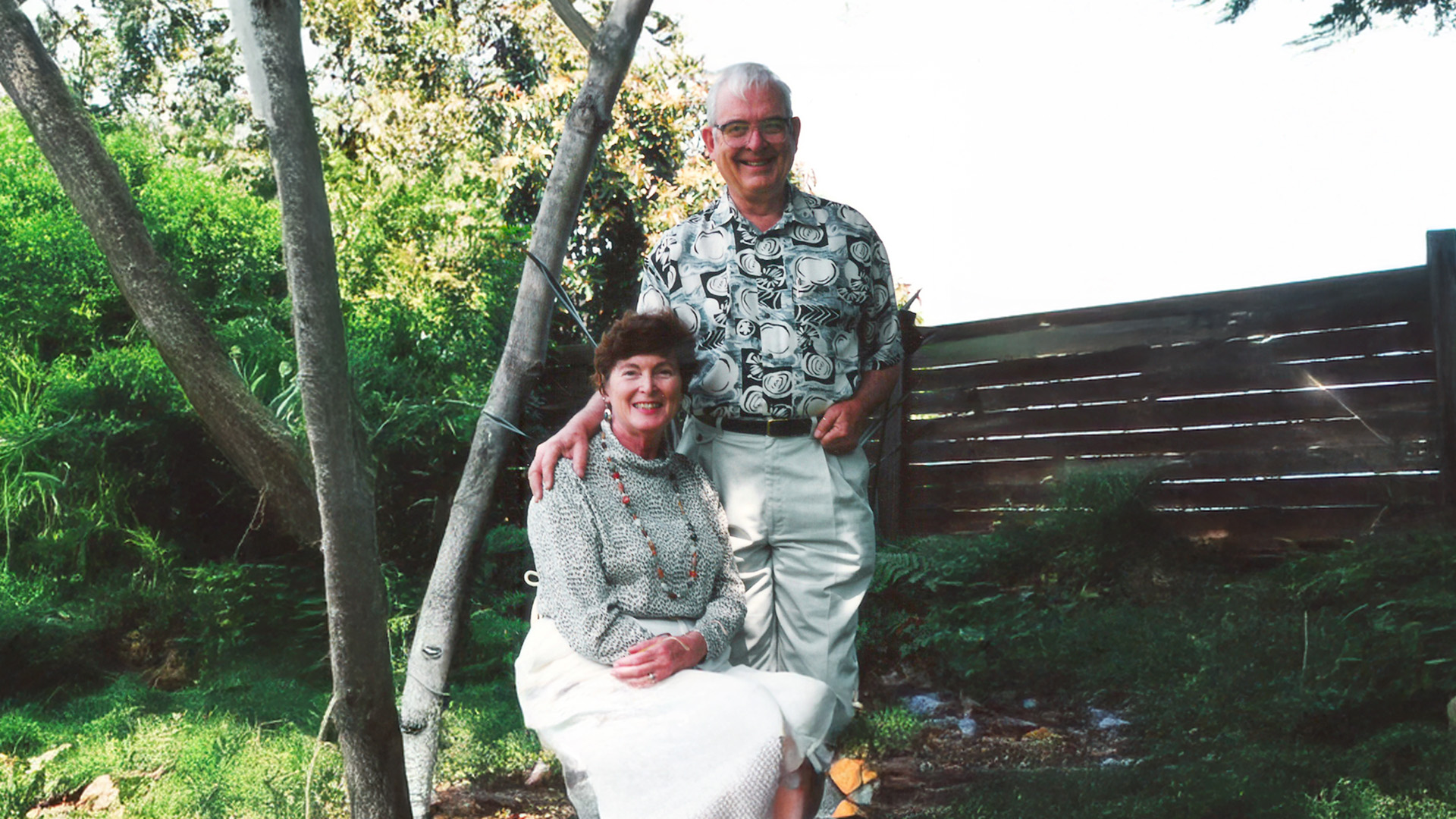 John Hood standing behind a seated Barbara outside