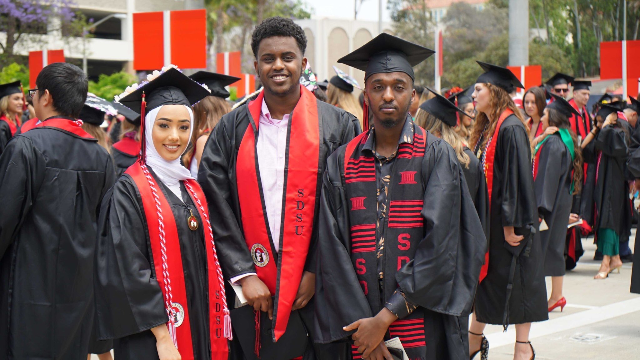 Photo of three Undergrad Students in graduation regalia