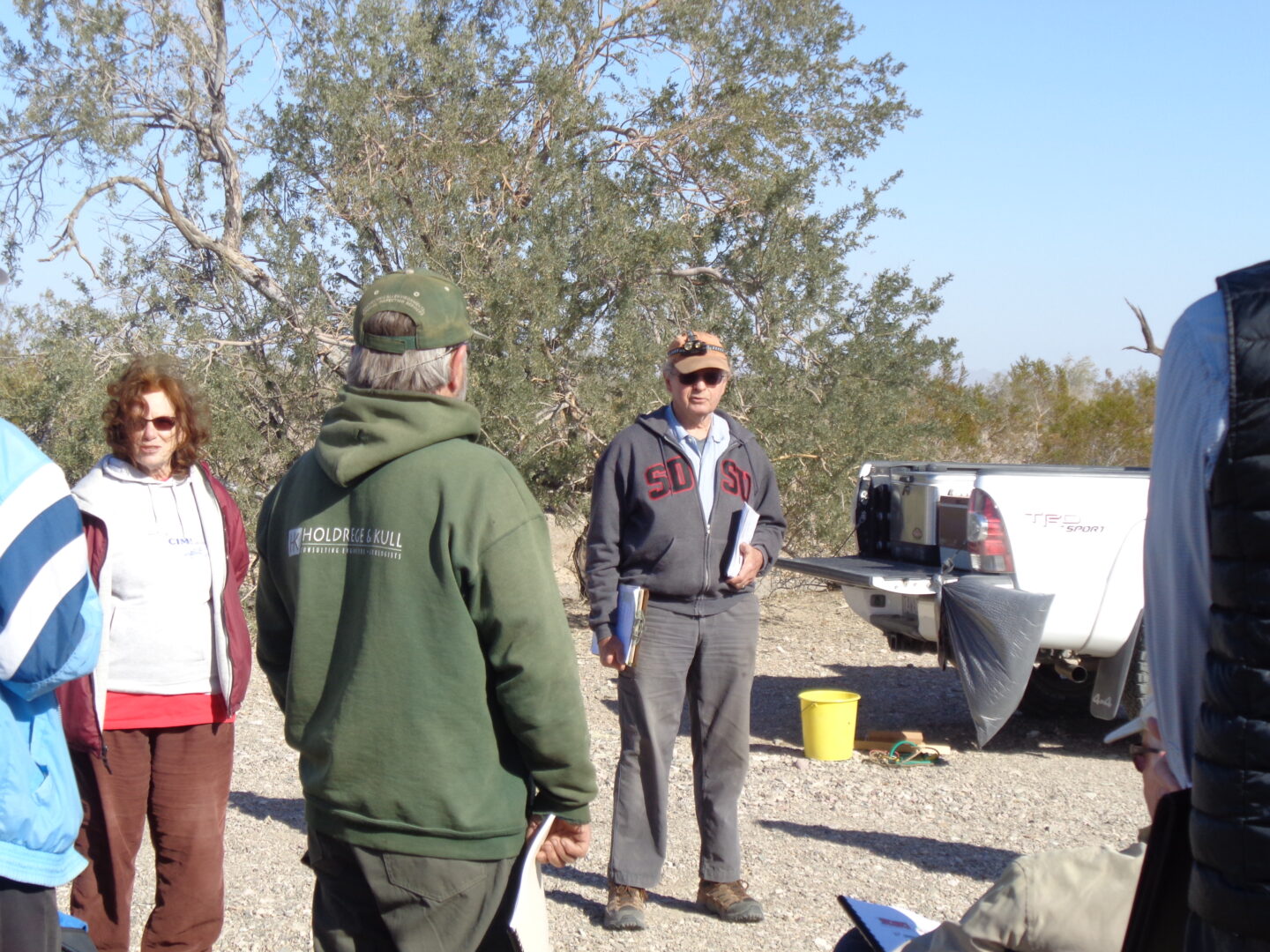 Alumni gather around Joe Corones at the campsite