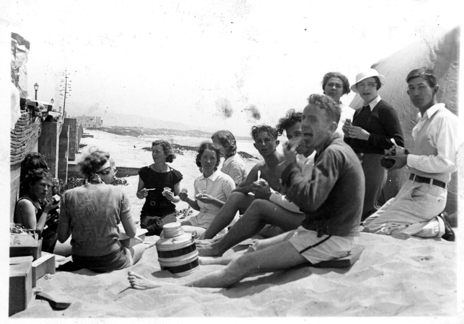Men and women sit on the beach in Ensenada eating and drinking