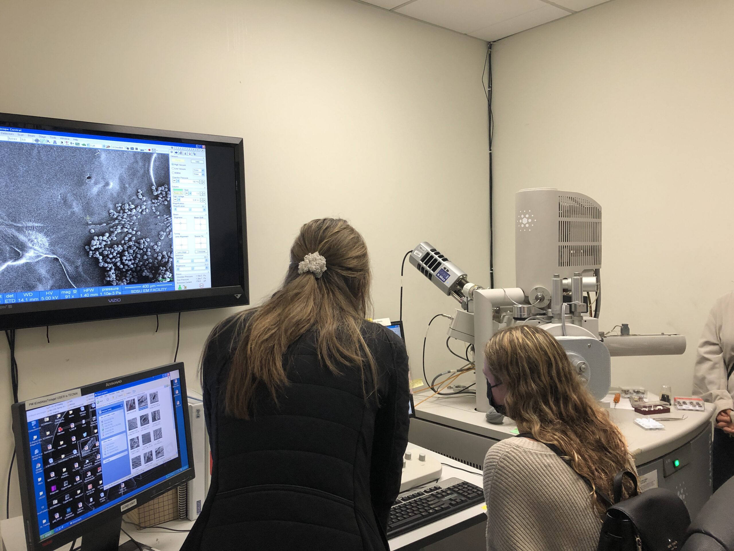 An SDSU student shows a high schooler a pollen sample using an electron microscope