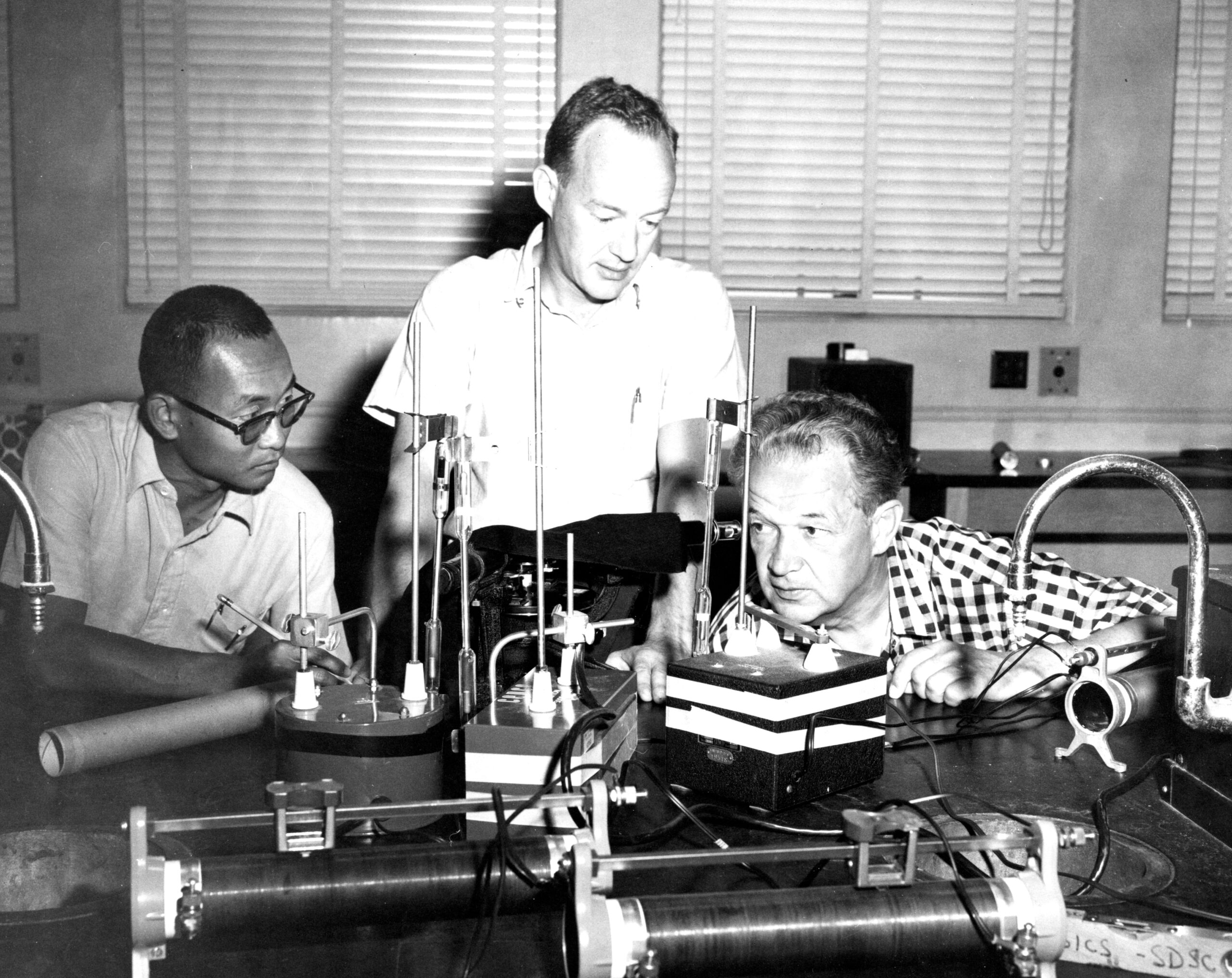 Three men in science classroom using spectroscopes