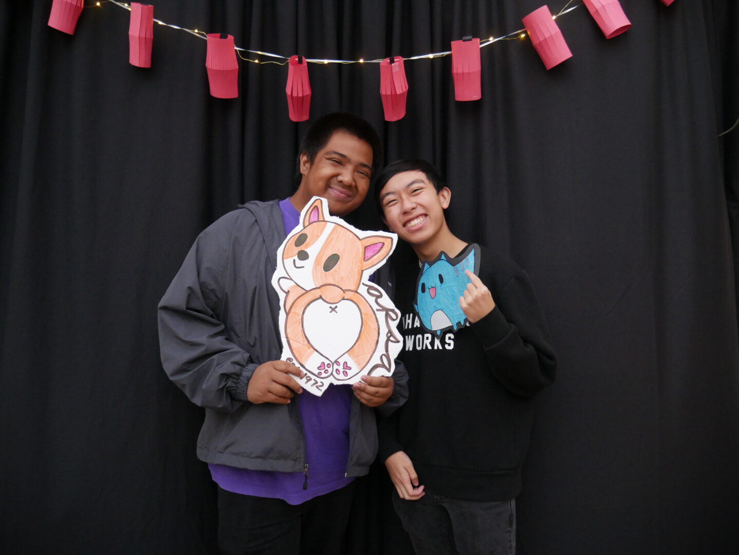 Jeffrey Cardinez (left in purple shirt, holding cardboard cutout of a corgi) stands with his mentee, Jeffrey at an APSA event.
