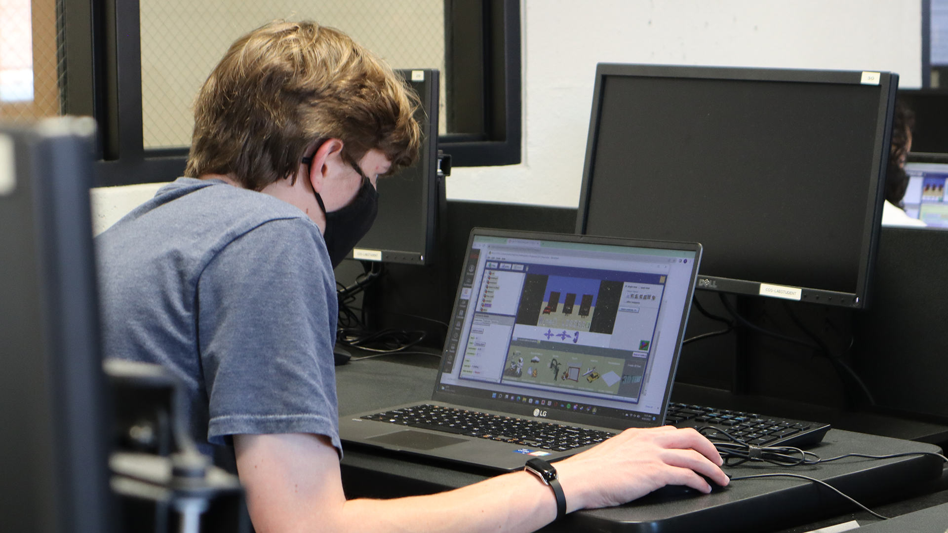 A student wearing a mask programs in ALICE on a laptop in a computer lab