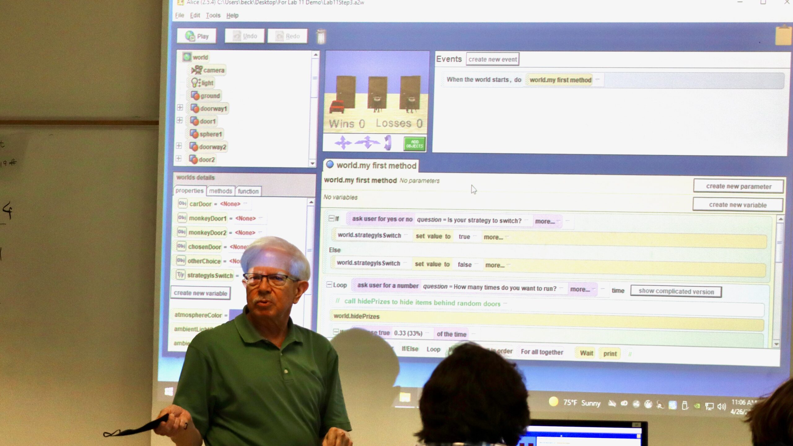 Professor Leland Beck, a man with white hair and glasses and a green shirt, explains ALICE programming projected on a screen in a classroom