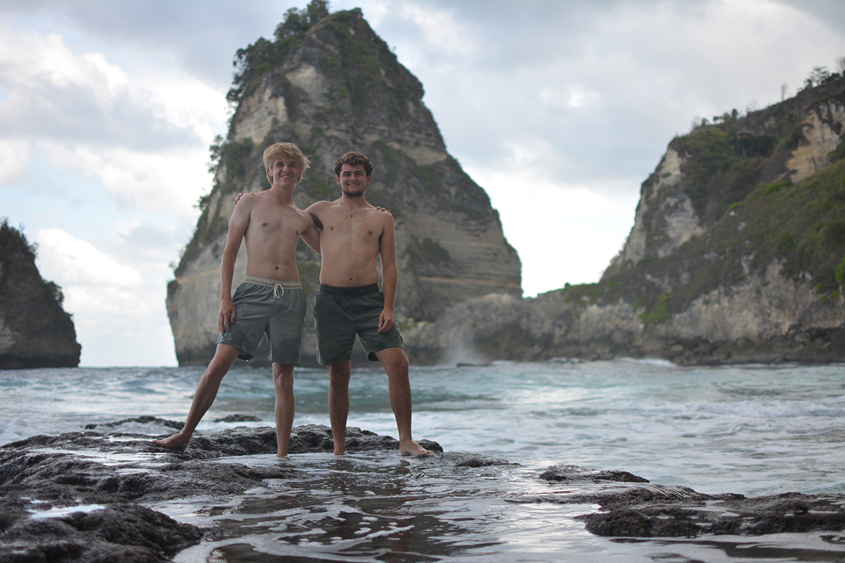 Scott and another student stand in a cove in Indonesia in swim trunks