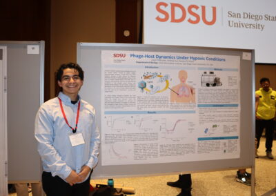 Student stands next to his poster on using hypoxic chambers with phages