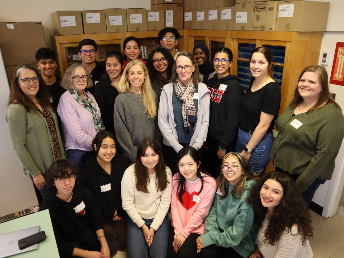 The four principal investigators who manage the Biotech Scholars program pose for a photo in the lab with their cohort of fourteen undergraduate students