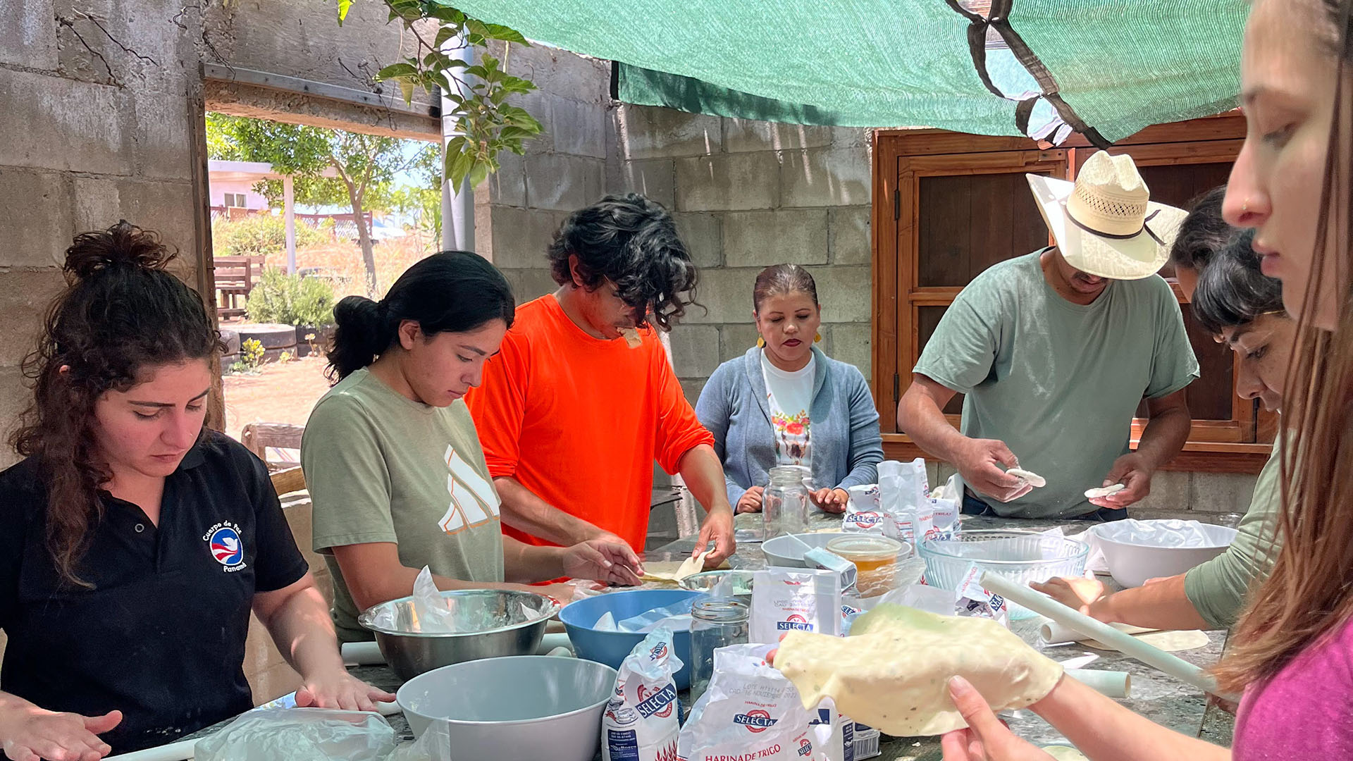 Students led by Rigo Aldama making tortillas from scratch in outdoor room.