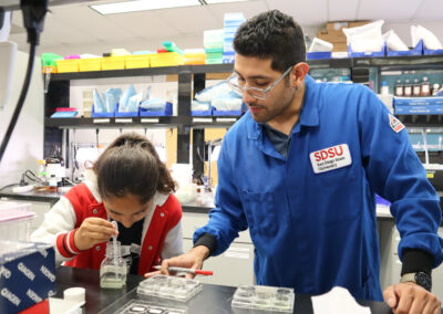 Daniel Noreña-Caro, a researcher in Zuniga’s lab, shows a student how to pipette algae samples