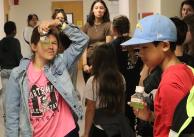 Local fifth grade students hold up algae samples they took care of and studied in the lab with undergraduate student Nicole Romero, from the Zuniga Lab, in the background