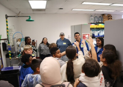 Fifth grade students excitedly hold up algae samples they’ve taken care of for a week, before examining them in an SDSU lab