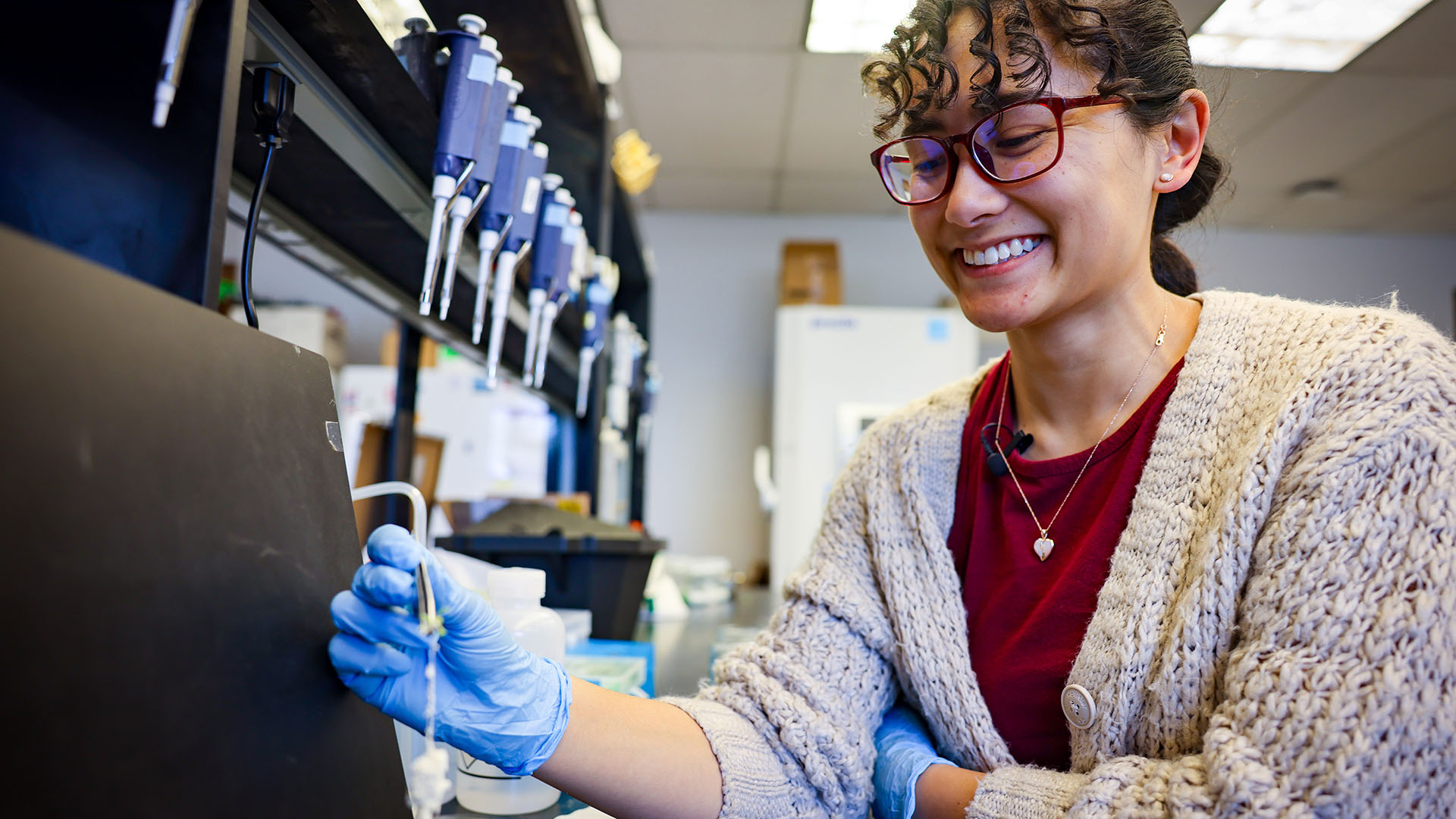 Closeup of smiling student in a lab filling a test tube.